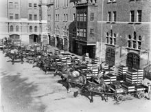 Münchensbryggeriets gård med ölutkörare och hästdragna vagnar lastade med flaskbackar.