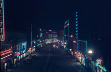 Kungsgatan österut mot Stureplan i mörker med neonskyltar. Tv. ligger Kungsgatan 18 och 14. T.h. 19 och 17