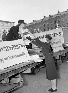 Östermalmstorg. Kampanj för Stadsmissionens pappersinsamling, frivilliga kvinnor från armé- marin- och flyglottorna deltog. Bilden visar, flyglottor som lastar tidningsbuntar på Stadsmissionens bil