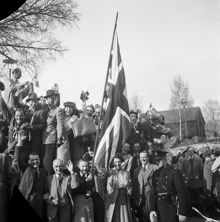 Fredsdagen den 7:e maj 1945 i Stockholm. 
Glada och flaggviftande människor firar freden.