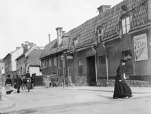 Folkliv och hästfordon vid Maria Högbergsgata 53-51 österut från Timmermansgatan. Handlare C A Lybergs viktualie- och speceributik t.h. Nuvarande Högbergsgatan 87-85