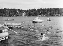 Bromma. Människor badar med flytvästar och livflottar