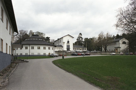 Vita stenbyggnader kring en gräsmatta.