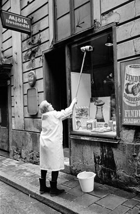 Maja Erikssons mjölkbutik från gatan. Maja Eriksson putsar skyltfönstret.