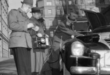 Polismännen Axelsson och Remblad från Gengaspolisen undersöker ett gengasläckage i en bil med hjälp av en koloxidindikator. T.h. Ingenjör Sieurlin från Gengasbyrån