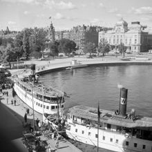 Nybrokajen med ångbåtar. Dramaten i fonden