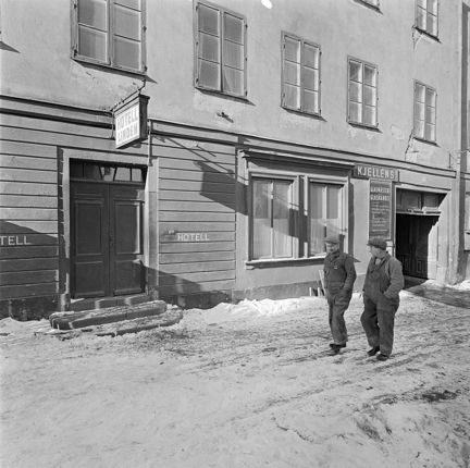 Klara Västra Kyrkogata 21. Hotell Linden. några män går förbi huset. det ligger snö på marken