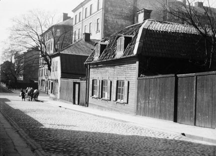 Wollmar Yxkullsgatan västerut. Till höger syns Wollmar Yxkullsgatan 4 med gammal trähusbebyggelse. Ett hästfordon syns vid korsningen mot Swedenborgsgatan.