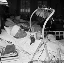 Vårdhemmet Högalid. Alfred Fröberg ligger i sin säng och tillverkar prydnadsfåglar (arbetsterapi)