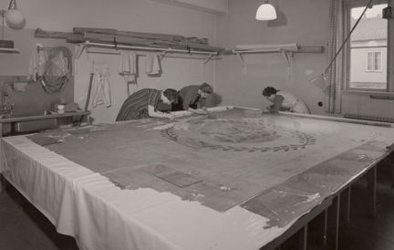 kvinnor arbetar böjda över en fana