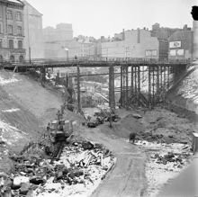 Vy norrut från Klarabergsgatan över rivningar och tunnelbanebygge kring platsen för blivande Sergels Torg. Mäster Samuelsgatan går via tillfällig bro.