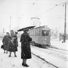 Vinterbild. Snöig gatumiljö där spårvagnslinje 9 tar sig fram