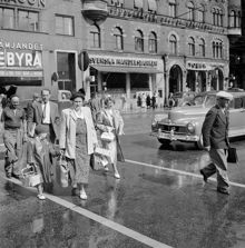 Vasagatan 12. Fotgängare går över gatan, vid en obevakad gul linje (ett övergångsställe)