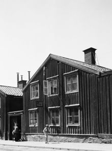 Timmermansgatan 44. En dam passerar genom porten och en pojke går förbi vid P A Arboréns skomakeri. Då kv. Bergsgruvan Större, nu kv. Postbonden