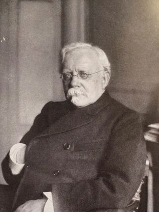 Svartvitt porträtt av professor Edvard Welander sittande i en fåtölj med ena handen instucken i kavajen.