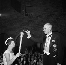 Hantverkargatan 1, Stadshuset. Invigning av Stockholms universitet. Kung Gustaf VI Adolf tänder den akademiska elden som bärs vidare av studenten Inga Broberg