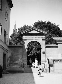 Några personer passerar södra kyrkogårdsporten till Katarina kyrka. Vy norrut från Södermannagatan