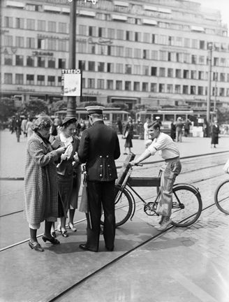 En polis, två damer, en ung man på cykel.