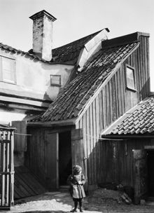 Ett barn står på gårdssidan av Västra Kvarngränd 6 och 8. Nuv. kv. Kvadraten ung. norr om Allhelgonagatan, tidigare Gotlandsgatan