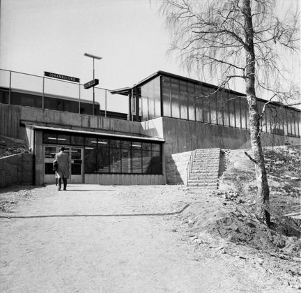 Stationsbyggnad sedd på håll. En man på väg mot ingången.