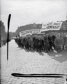 Demonstrationståg med banderoller "Mot nazisim och judeförföljelse" och "För frihet, arbete och demokrati" på Värtavägen mot Valhallavägen. I fonden kvarteret Djursborg.