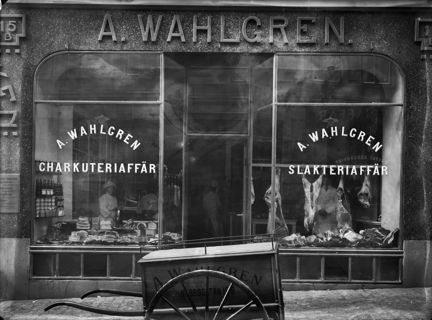 skyltfönster till en butik. framför står en kärra. 