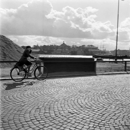 Strandvägen. Kvinna cyklar i blåsväder