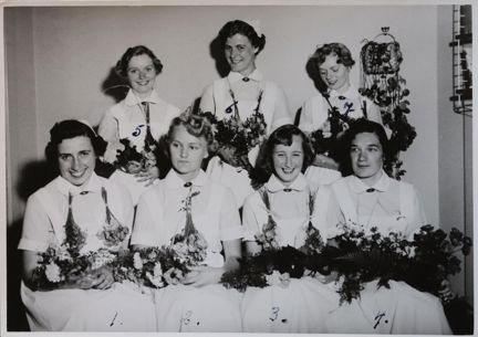 Svartvitt fotografi på flickor med blommor från Stockholms stads barnavårdsskola