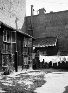 Tvätt hänger på tork över gården vid Styrmansgatan 20 (nuvarande 16). Trähuset omges av brandmurar