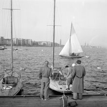 Kajen vid Söder Mälarstrand. Några män vid en segelbåt. Riddarfjärden och Norr Mälarstrand i fonden