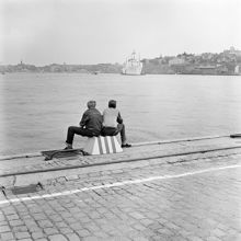 Från Skeppsbron mot Strömmen. I fonden det ankrade passagerarfartyget ""Argentina"". I förgrunden två sittande pojkar