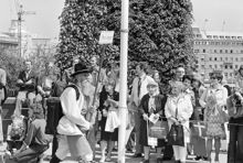 Reportage kring Kungabröllopet den 19 juni 1976. En man med dragspel på ryggen och skylten ""Mora Kompani"" tågar över Norrbro. Åskådare, en del med svenska flaggan i handen, står längs broräcket