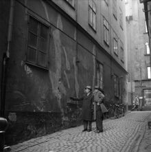 Drakens gränd. Stora delar av den gamla bebyggelsen mellan Österlånggatan och Skeppsbron håller på att rasa. Stadsantikvarie dr Gösta Selling och antikvarie Hans Hansson studerar en rämnad vägg