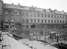 Kv. Järnplåten är rivet. Färghandeln ligger vid Oxtorgsgatan 5 och Skyltindustri AB vid Oxtorgsgatan 7, kv. Uppvaktarens norra sida. Här ligger nu T- Hötorget i hörnet av Sveavägen och Kungsgatan