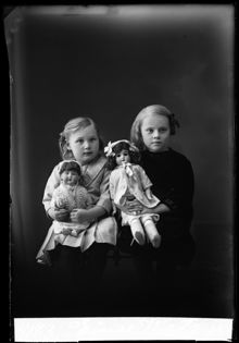 Grupporträtt av flickorna Einis Watz och hennes syster Ingeborg, med dockor.