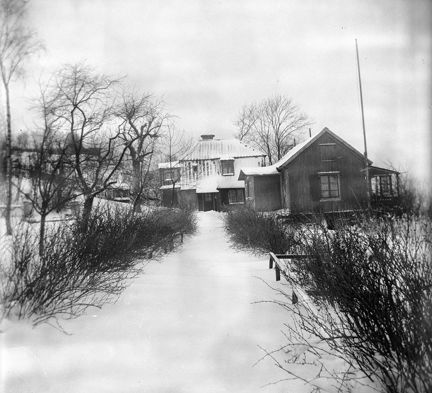 Vinter. En stig leder upp till en samling gamla hus
