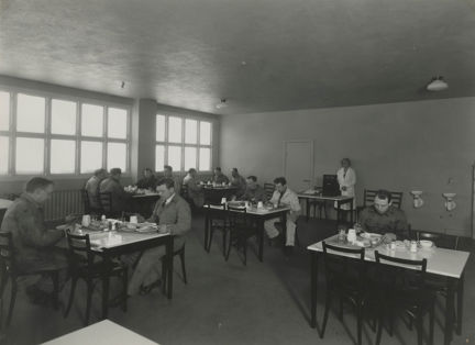 Män klädda i overall äter lunch vid olika bord.