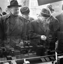 Män studerar kameror i skyltfönstret till en fotoaffär