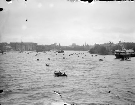 Vy mot väster över Saltsjön med HS Svensksund som anländer till  Stockholm med kvarlevorna efter de förolyckade männen från Andréexpeditionen. I fonden Gamla Stan, Norrmalm och Skeppsholmen.