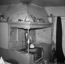 Interiör från köket i Anneboda gård med murad spiskåpa, vedspis och bakugn.