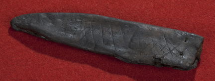 Medeltida knivslida av läder med rutmönster, rombiska rutor. Fotograferad mot röd bakgrund.. 