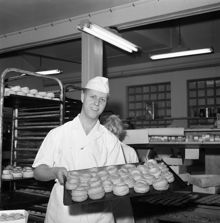 En bagargesäll visar upp en plåt med bullar