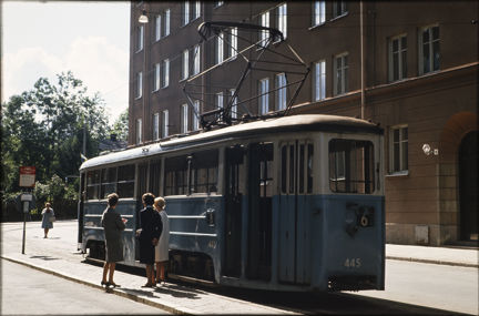 Tre kvinnor står vid hållplats bredvid spårvagnen på Södermalm.