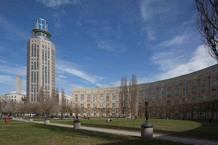 Fatbursparken med gräsmatta, träd, skulpturer i brons och Bofills båge och söder torn.