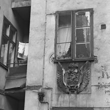 Drottninggatan 38, gården. Brandkontorets skylt sitter under fönstret. I fönstret hänger prickiga gardiner med volanger