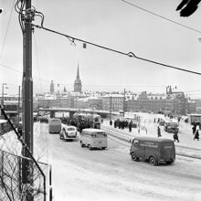 Katarinavägen. Bilar tar sig fram genom snön vid Slussen. Vy mot Gamla Stan