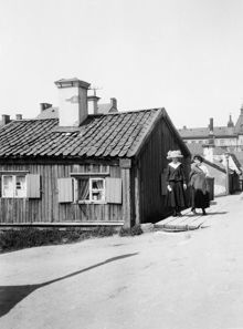 Två kvinnor står vid hörnet av Bergsprängargränd 5 och Borgmästargatan 16. Nuv. Mäster Pers Gränd, nordväst om Sofia kyrka