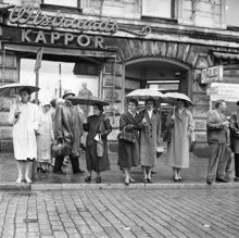 Vasagatan 22. Folk på väg över gatan i ett regnigt och blött Stockholm