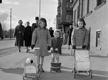 Tre flickor med dockvagnar promenerar
