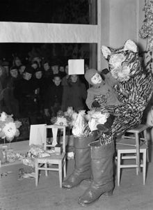 Hamngatan 16, Singers. Mästerkatten gör sitt årliga besök. Många barn hade kommit för att ge leksaker till katten, och därmed hjälpa tomten att samla in julklappar till fattiga barn